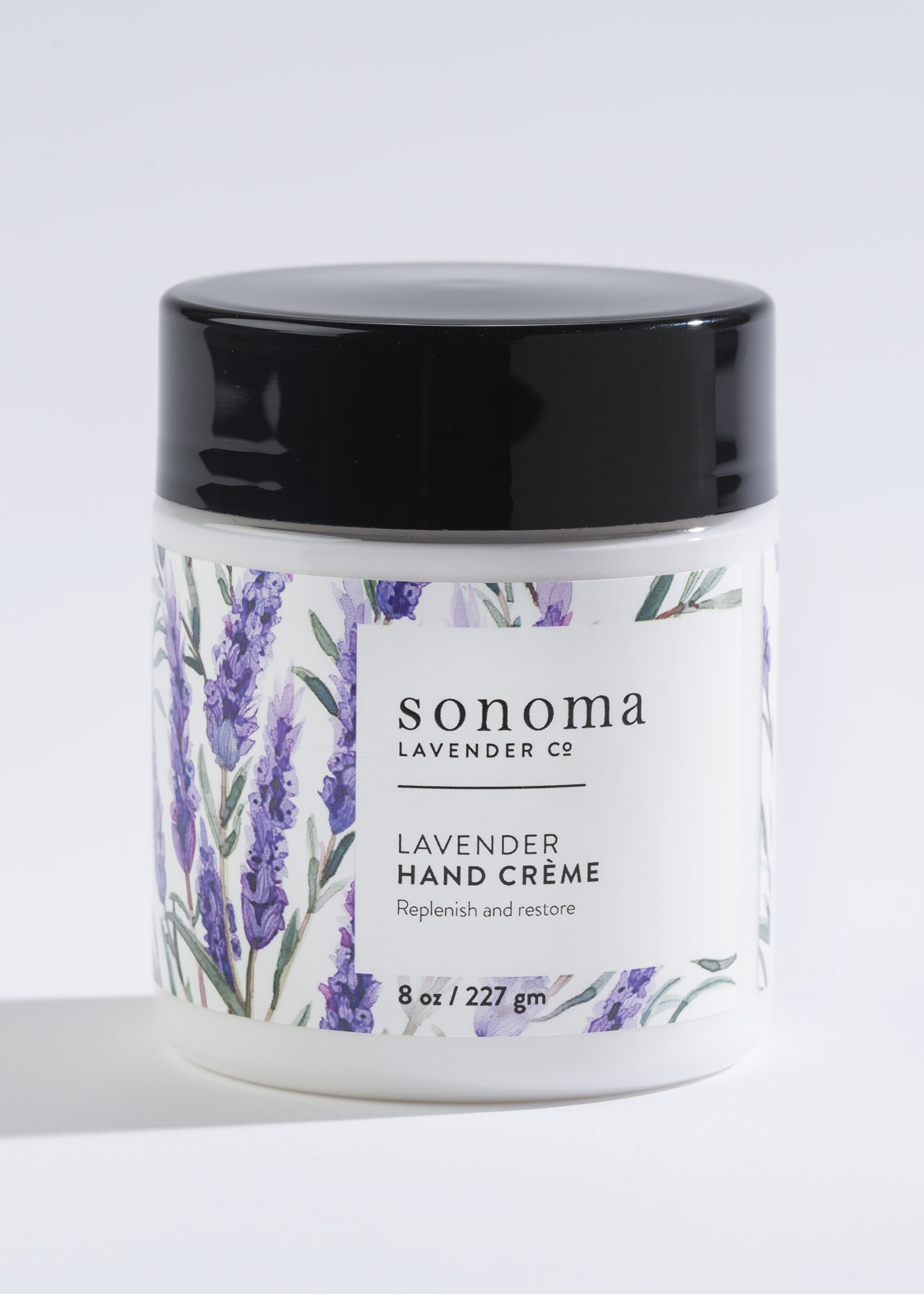 Jar of lavender hand creme with black lid and illustrated lavender sprigs on the label