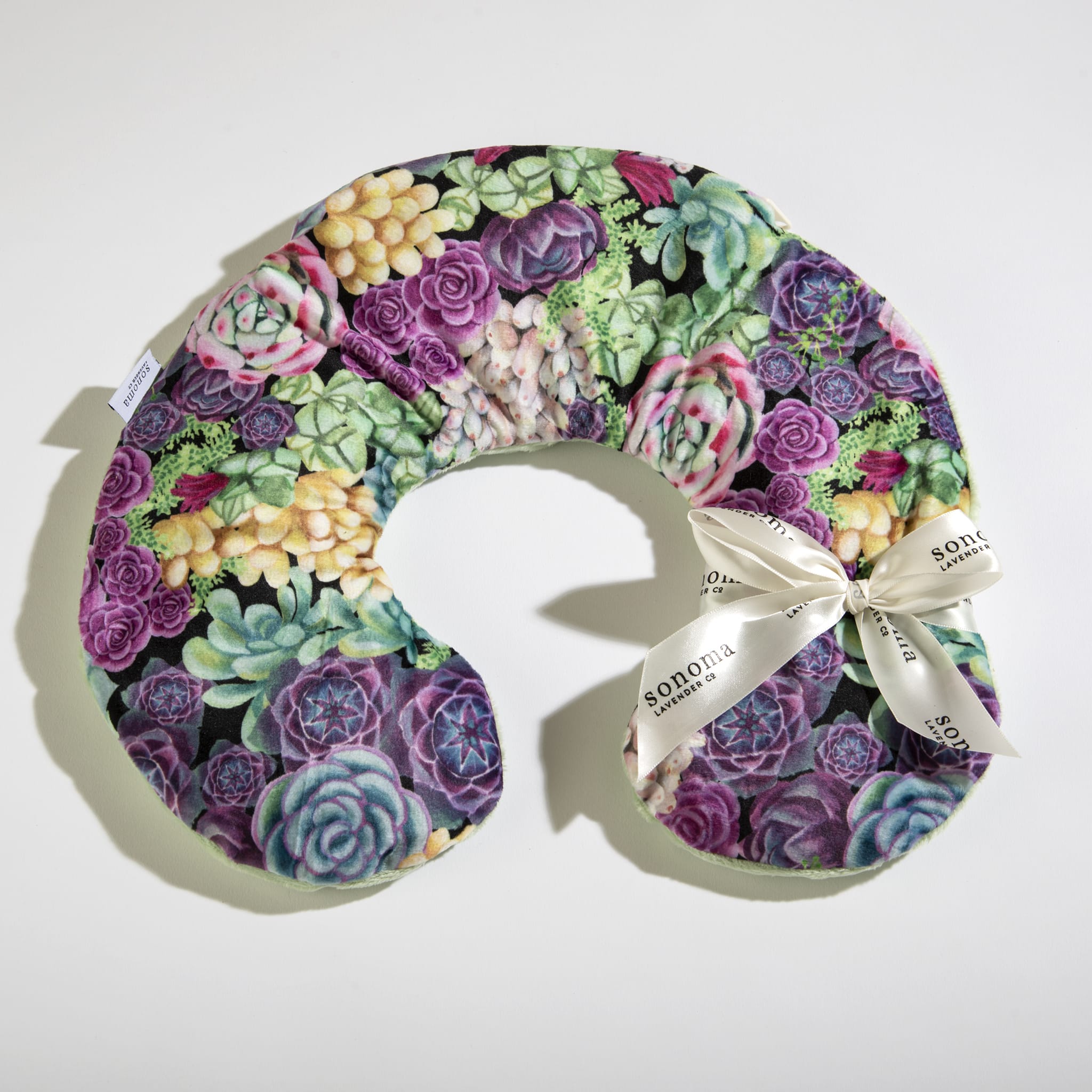 U-shaped neck pillow with colorful succulent pattern and a cream ribbon bow