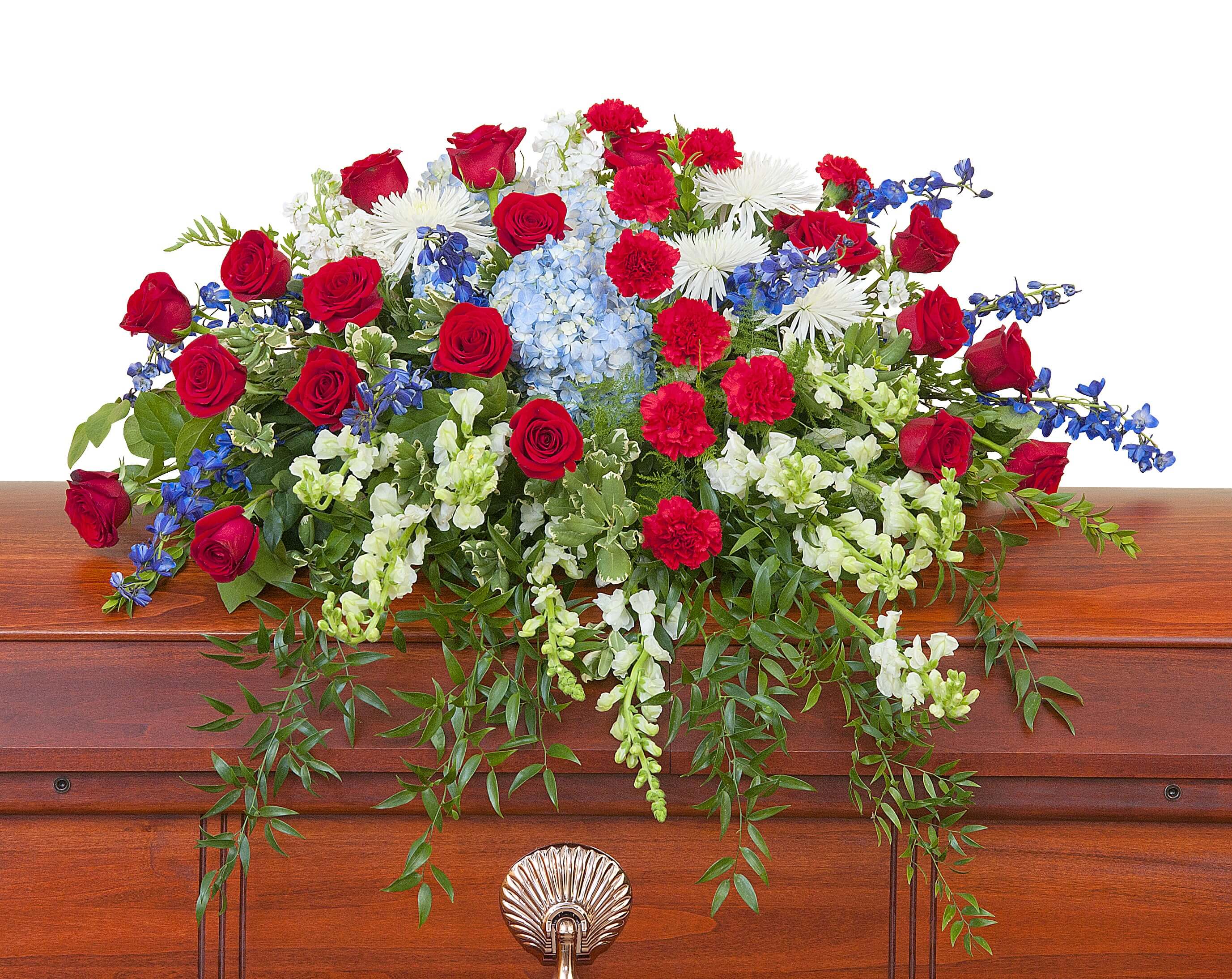 Red, white, and blue casket spray with roses, carnations, and mixed flowers on a wooden casket
