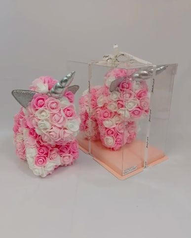 Pink and white rose-covered unicorn figurine with silver horn, one displayed in a clear gift box.