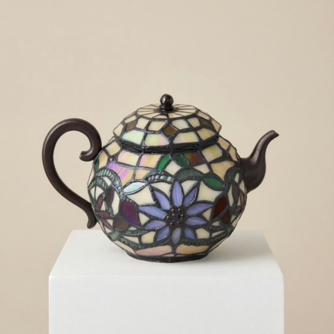 Decorative mosaic teapot with floral pattern on a white pedestal