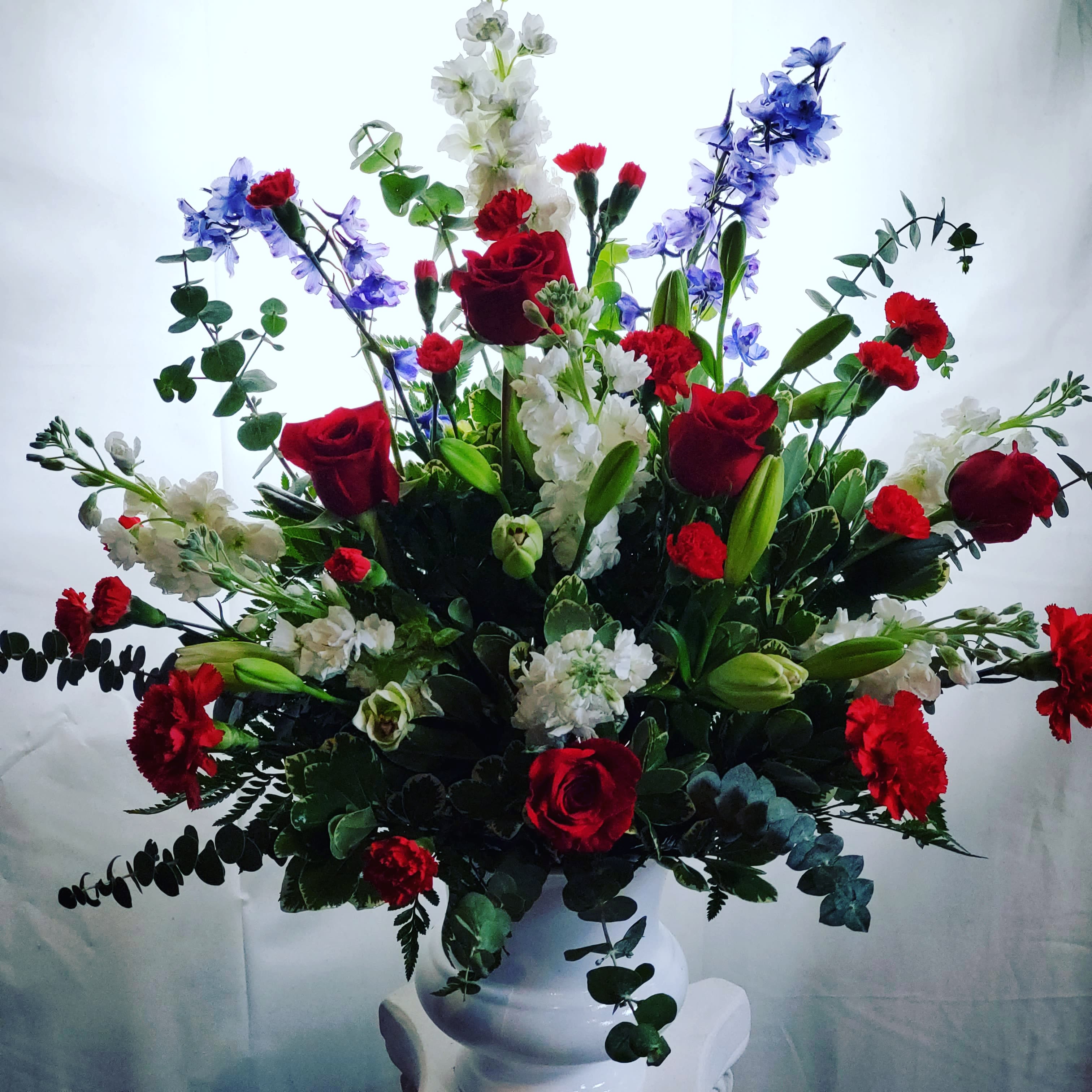 With Distinction by Teleflora - A dazzling display of patriotic red, white and blue flowers sends a silent yet poignant statement about hope, freedom and the strength to endure. This proud bouquet is a testament to life that is sure to be appreciated. 