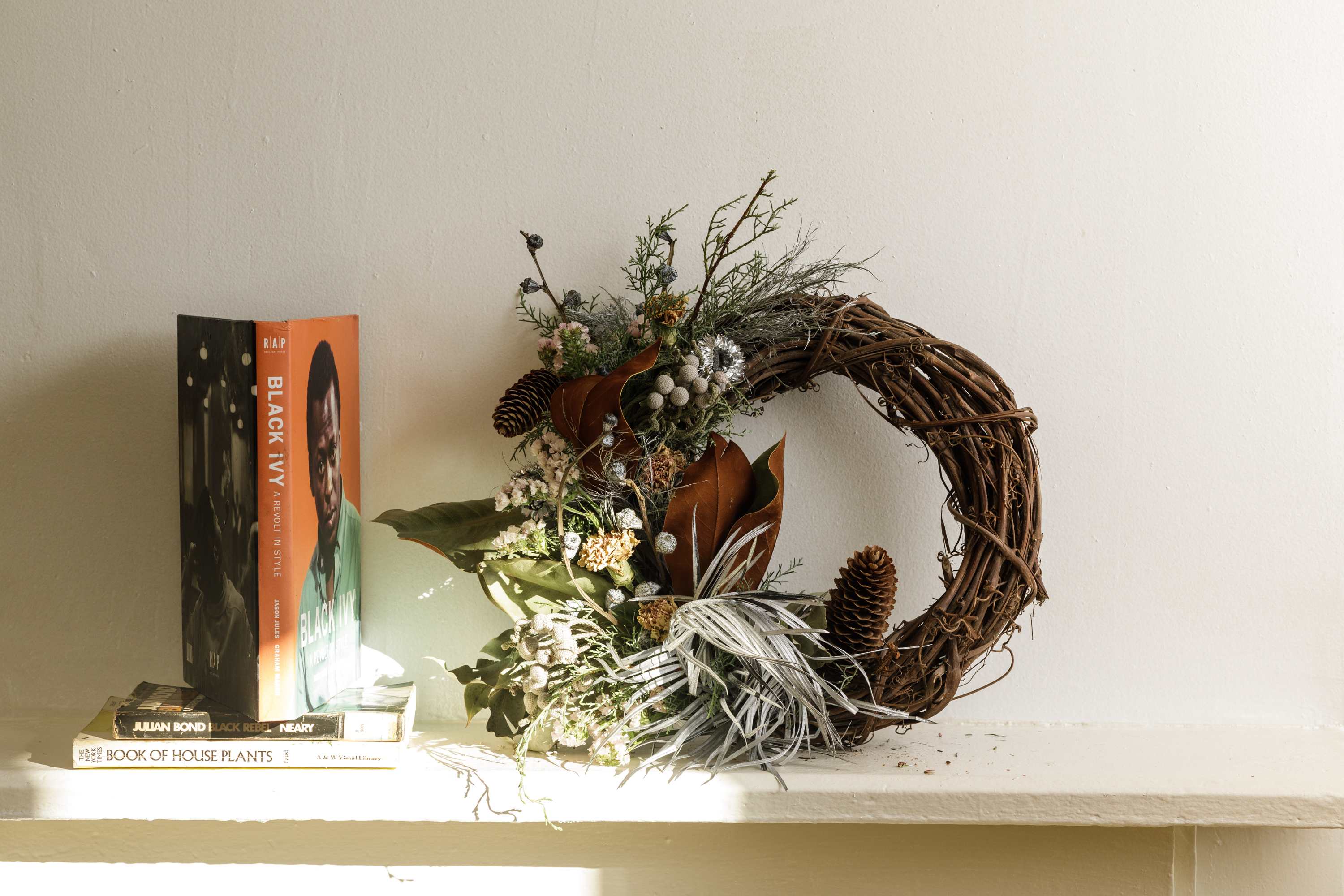 Rustic wreath with pinecones and dried florals beside stacked books