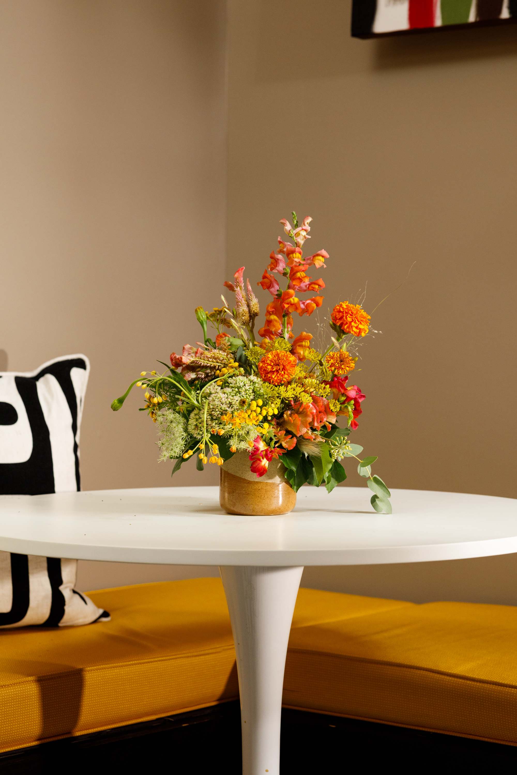 Colorful mixed flower arrangement in a gold vase on a white table