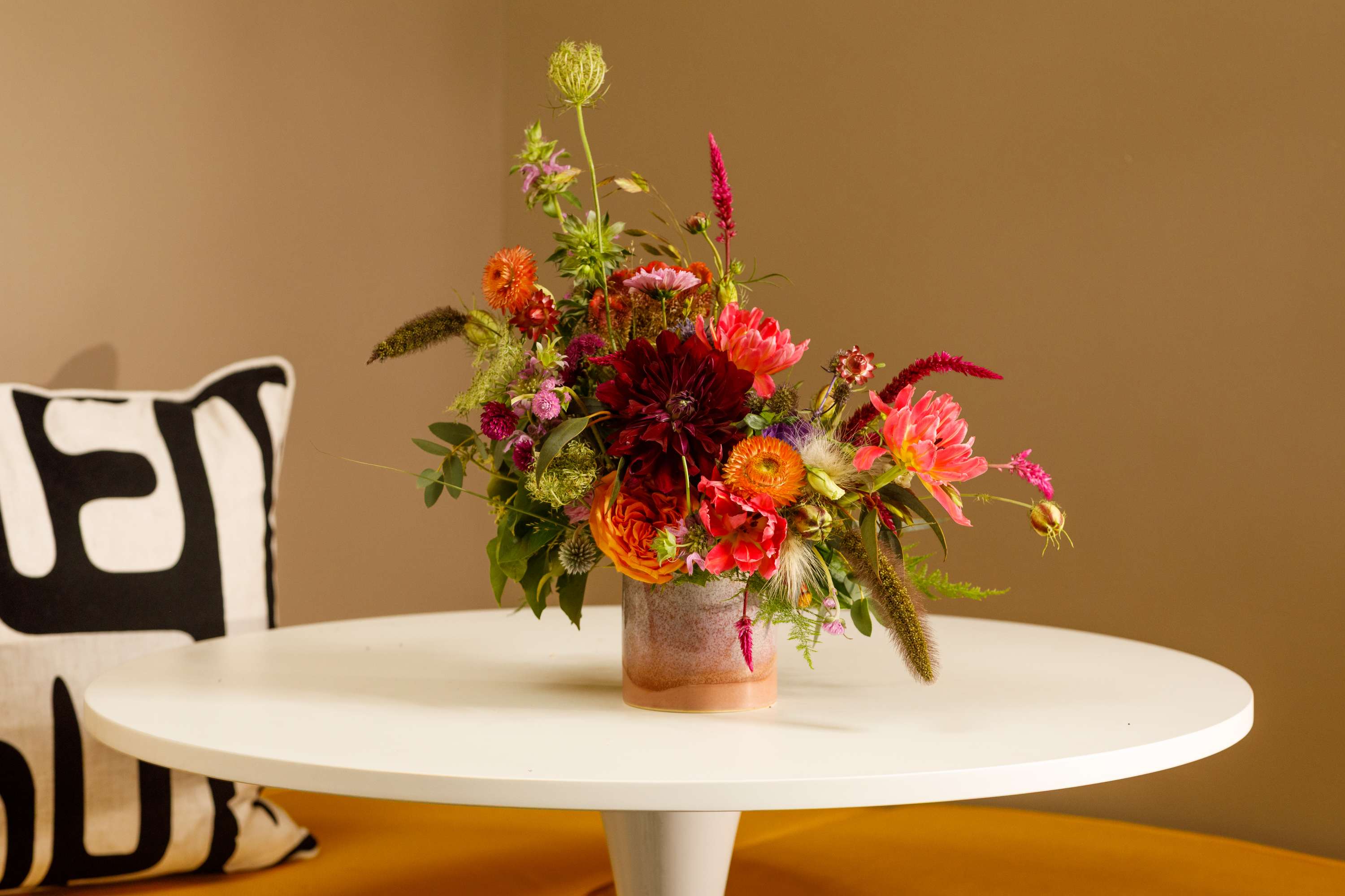 Colorful mixed flower arrangement in a low glass vase on a white table