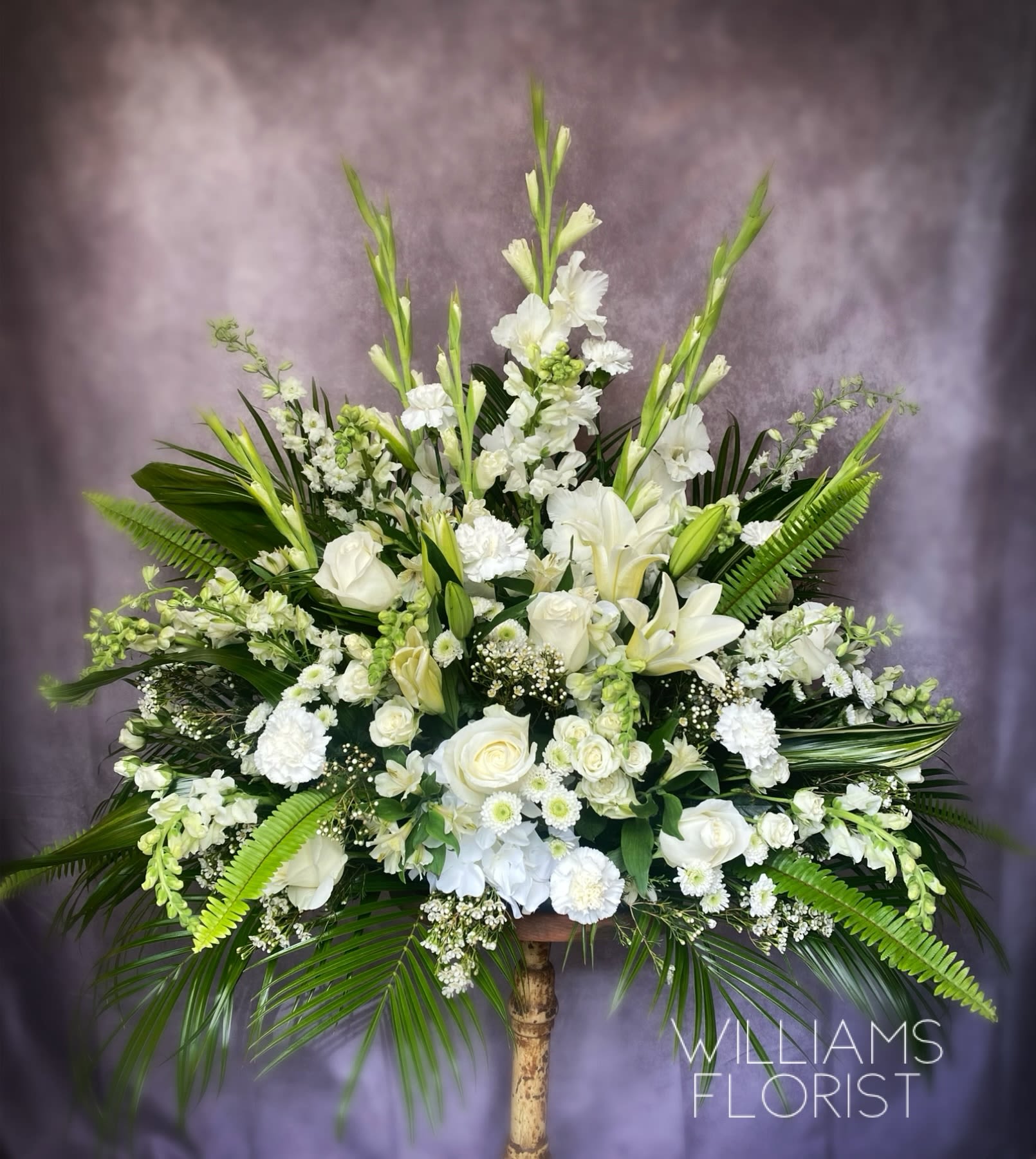 Serene Reflection Bouquet - Your love will be warmly felt by the family with this lovely gift of white roses and other favorites. Tasteful and elegant it is a beautiful choice. The exquisite bouquet includes white roses white alstroemeria white carnations white snapdragons and white spider chrysanthemums accented with assorted greenery.