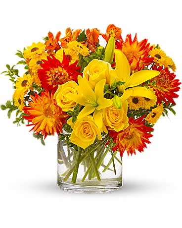 Yellow and orange flowers arranged in a clear glass vase