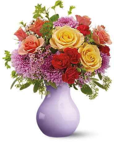 Mixed bouquet of roses and purple flowers in a lavender vase