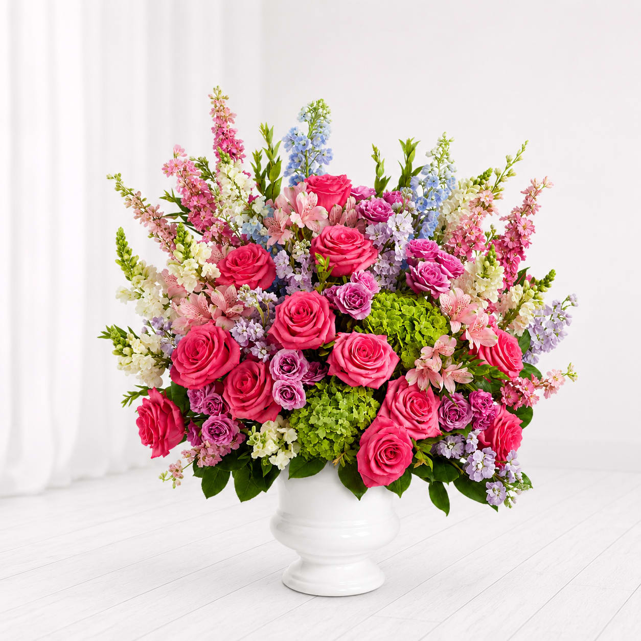 Garden of Memories Sympathy Bouquet - Softly gathered with graceful garden blooms, the Garden of Memories Sympathy Bouquet features vibrant pink roses, lush green hydrangea, pastel stock, alstroemeria, and delicate seasonal flowers arranged in a timeless white urn vase. Designed to bring comfort and beauty during difficult times, this elegant arrangement offers a heartfelt expression of love, remembrance, and support.