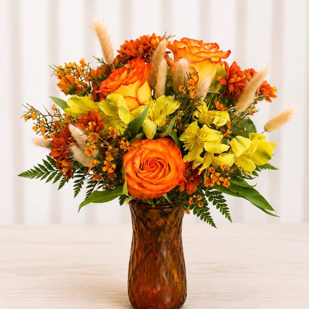 Orange and yellow flower arrangement in an amber glass vase