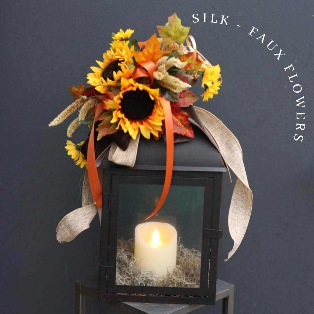 Silk sunflower arrangement on a black lantern with a lit candle inside