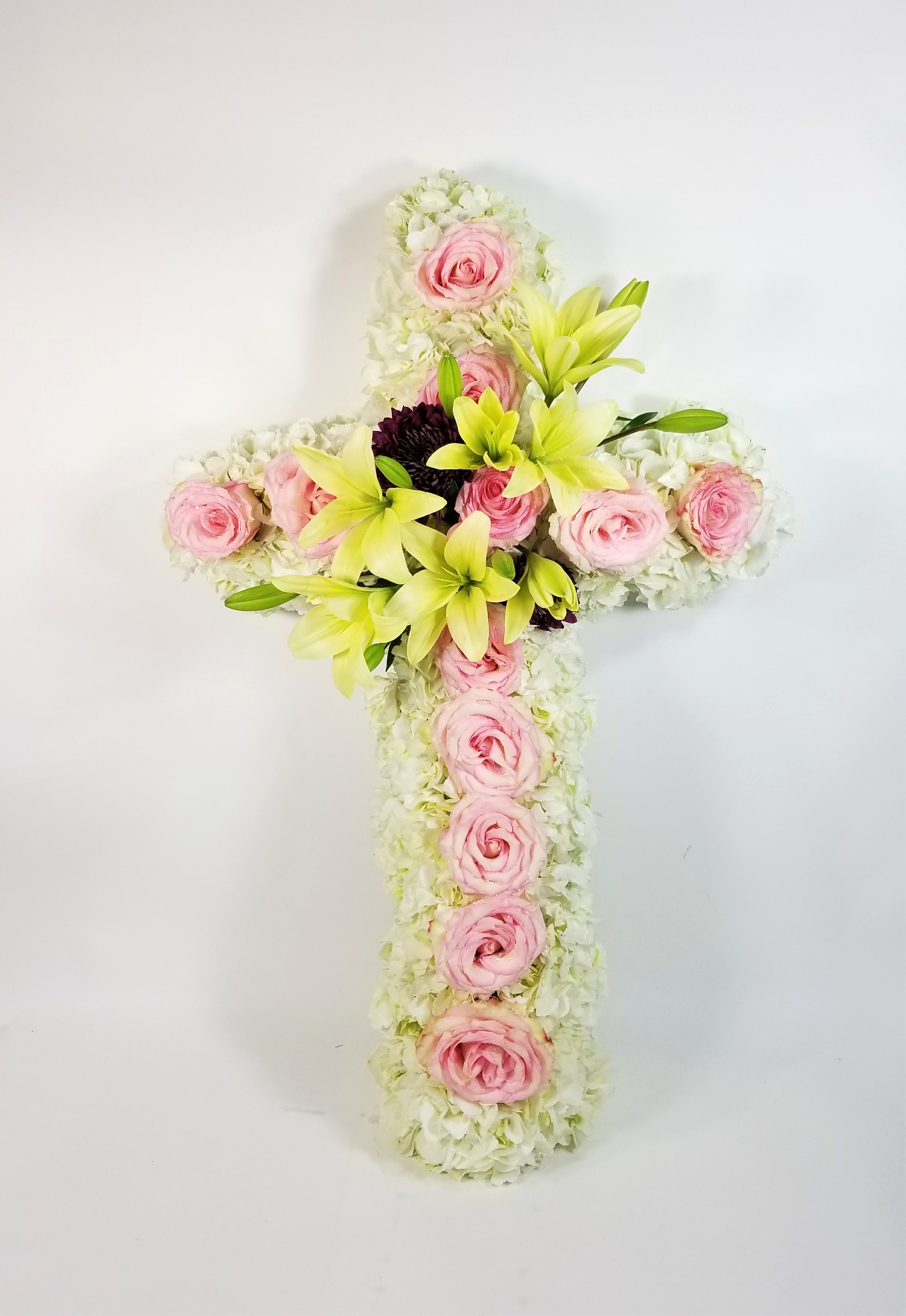 Floral cross with pink roses and pale lilies on a white background