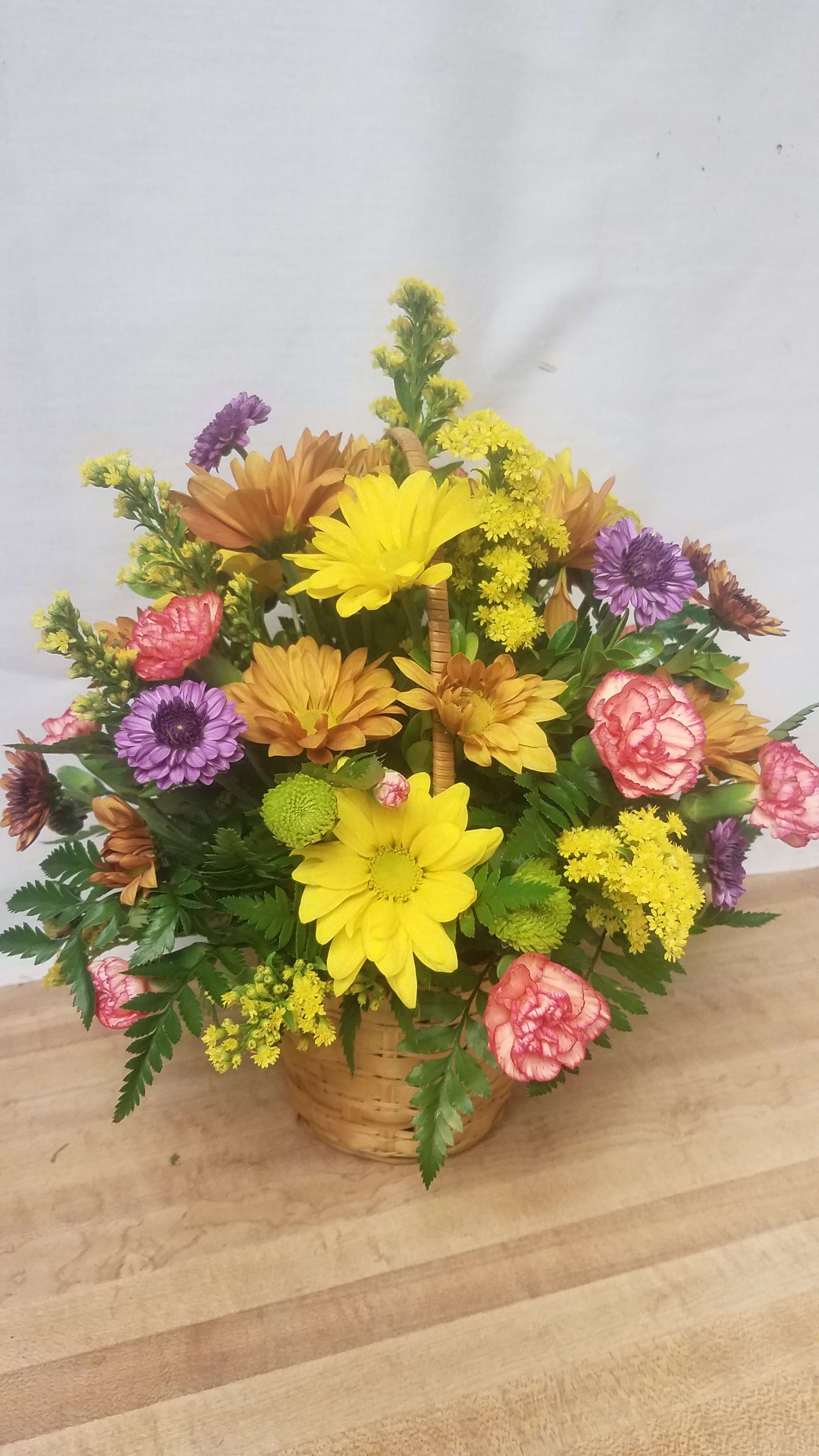 Basket arrangement of yellow, purple, pink, and orange flowers