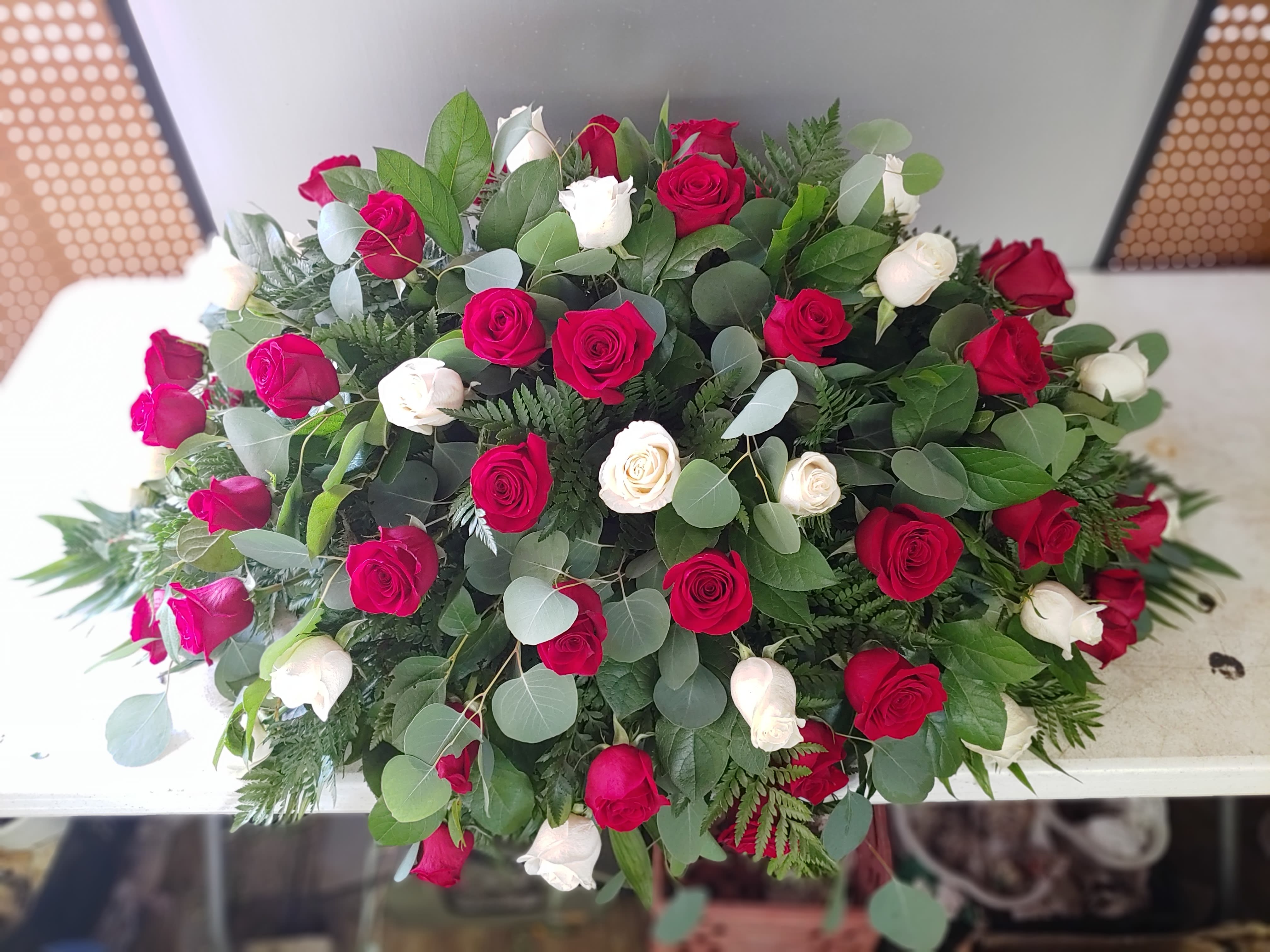 Large bouquet of red and white roses with mixed greenery