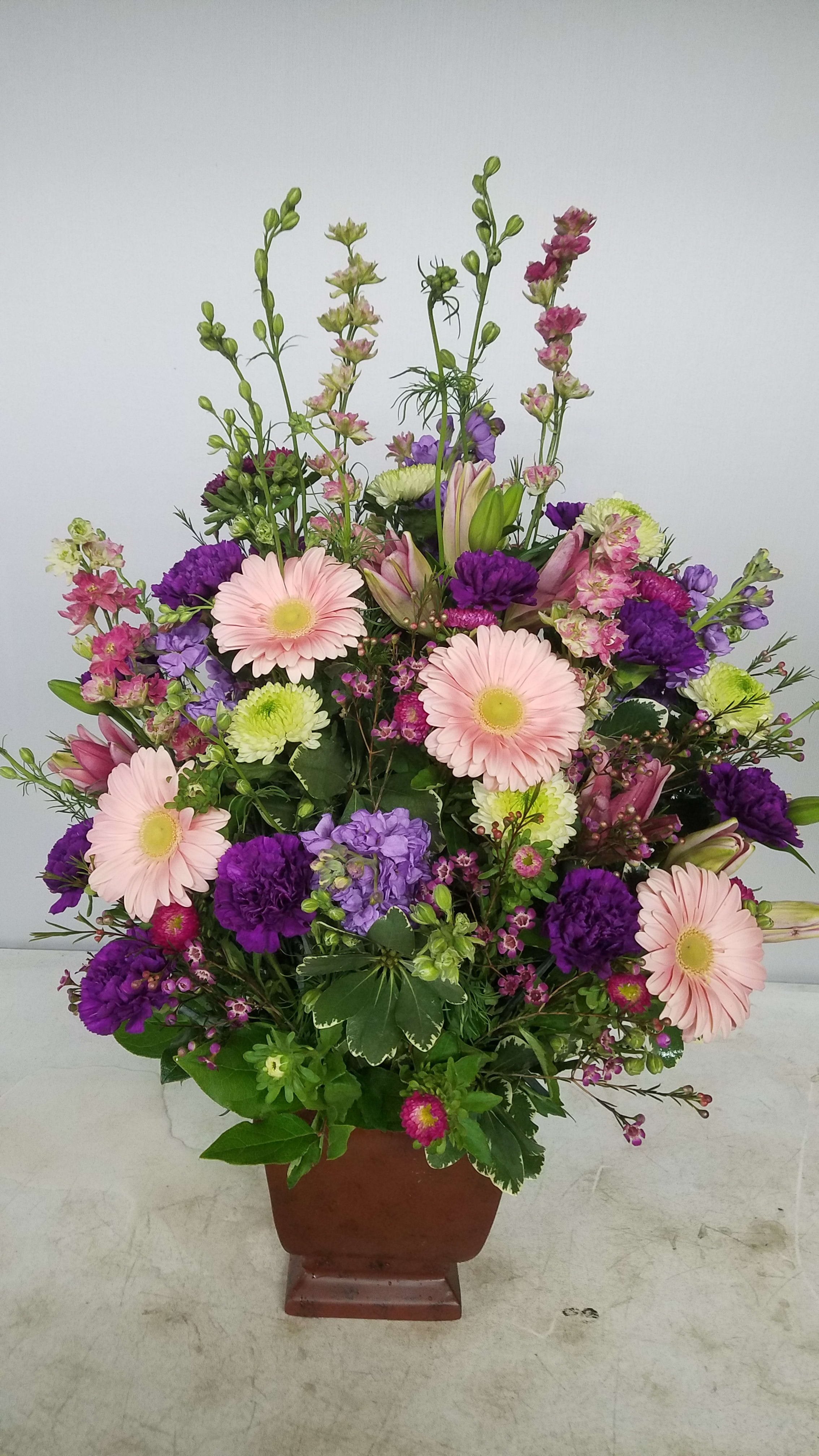 Mixed pink, purple, and green floral arrangement in a brown urn