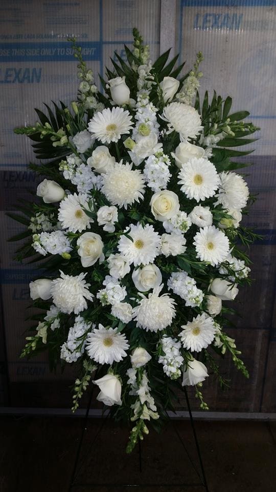 White funeral spray with roses and daisies on a stand