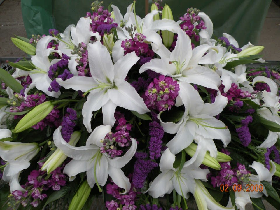 White lilies and purple flowers in a dense arrangement