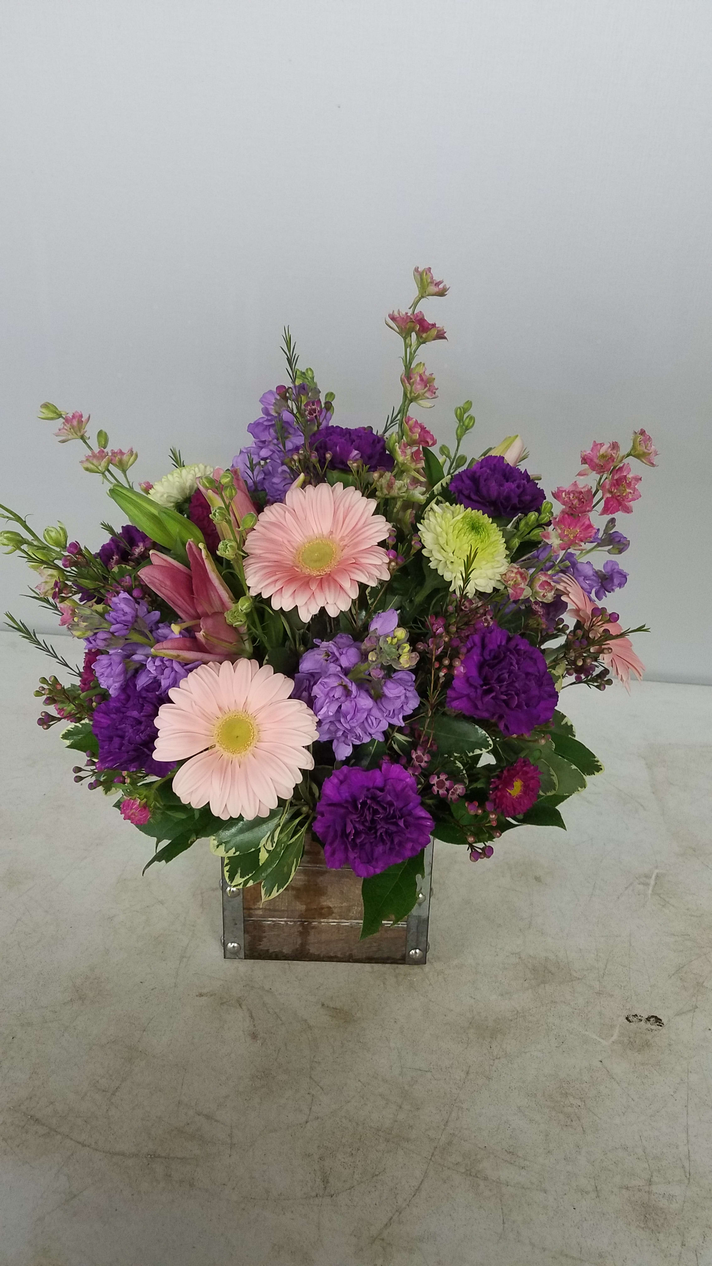 Mixed bouquet with pink gerbera daisies and purple flowers in a wooden box