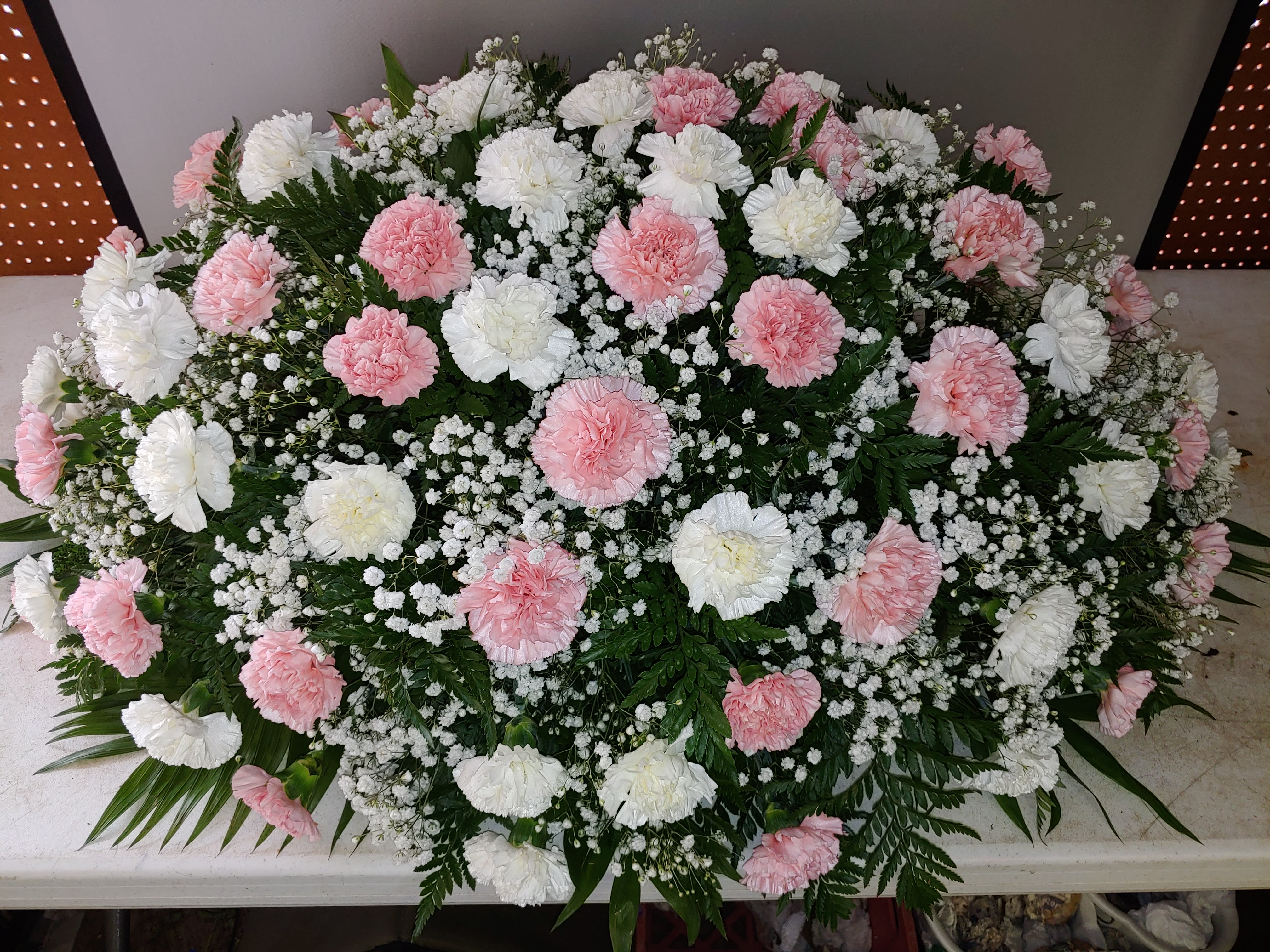 Pink and white carnation casket spray with baby's breath
