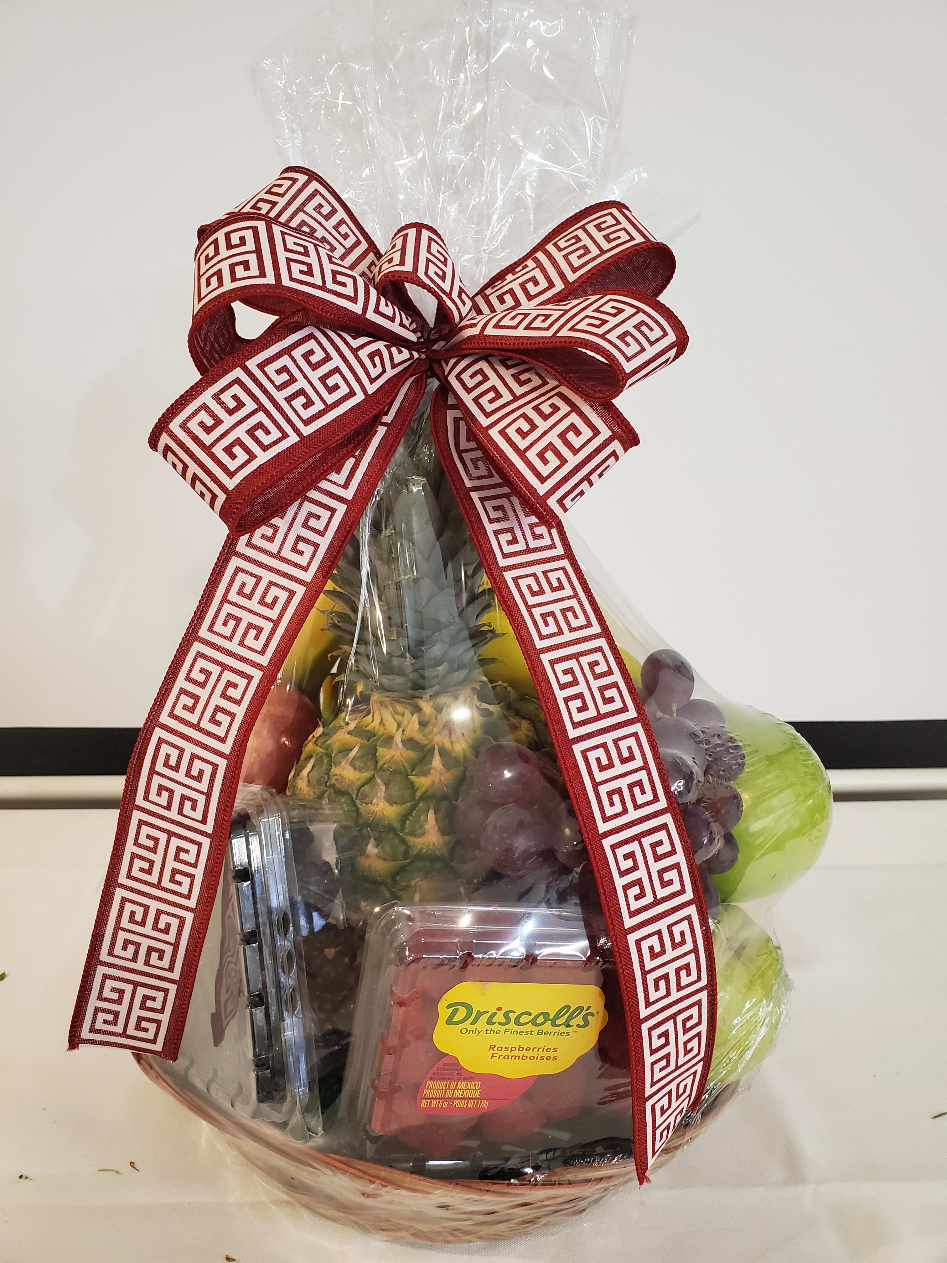 Fruit basket wrapped in clear plastic with a red patterned bow