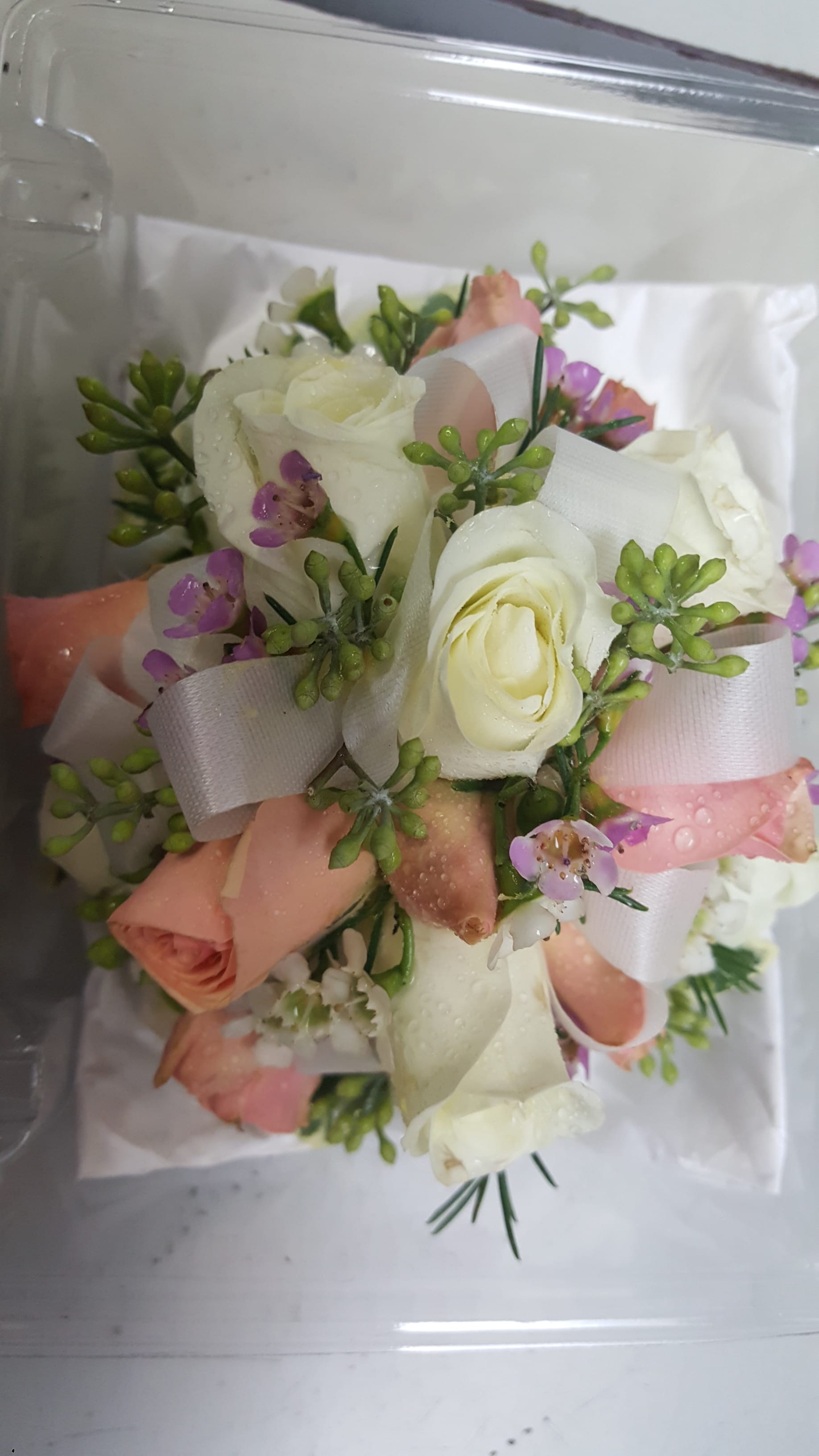 Small bouquet of white and blush roses with purple accents and ribbon