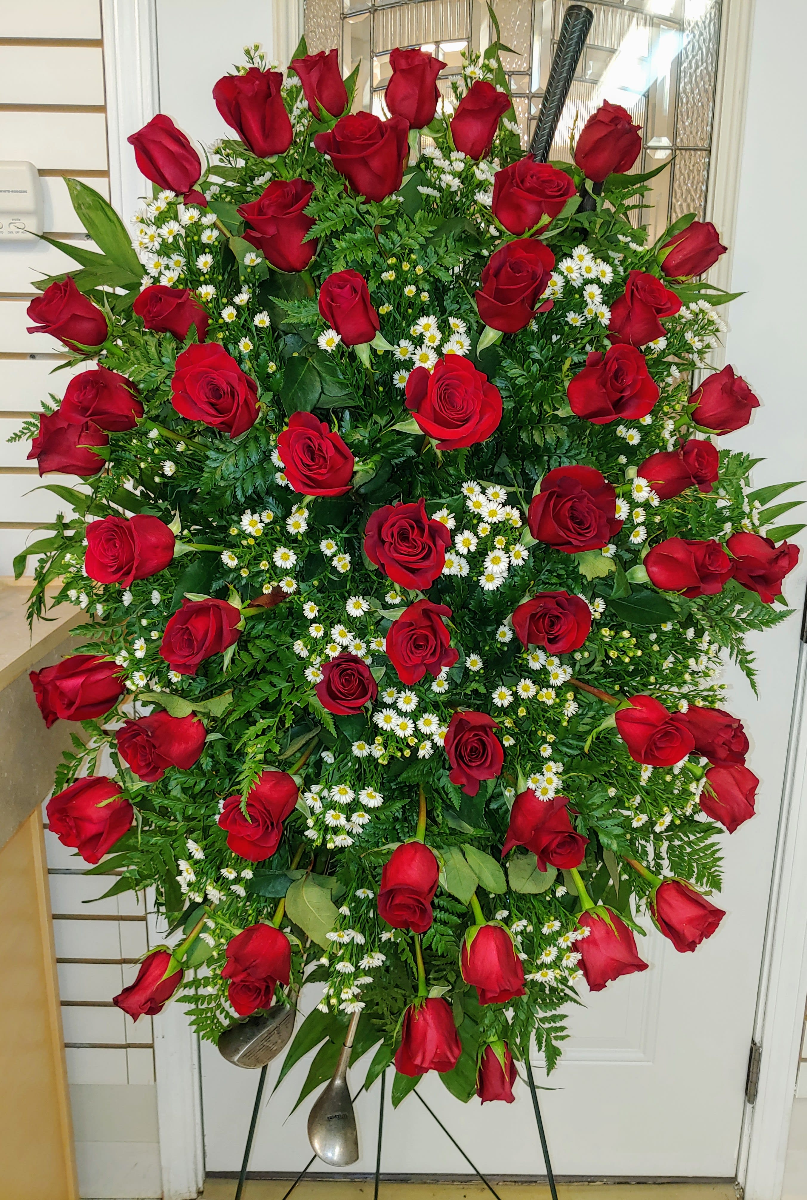 Large standing spray of red roses and white daisies on an easel