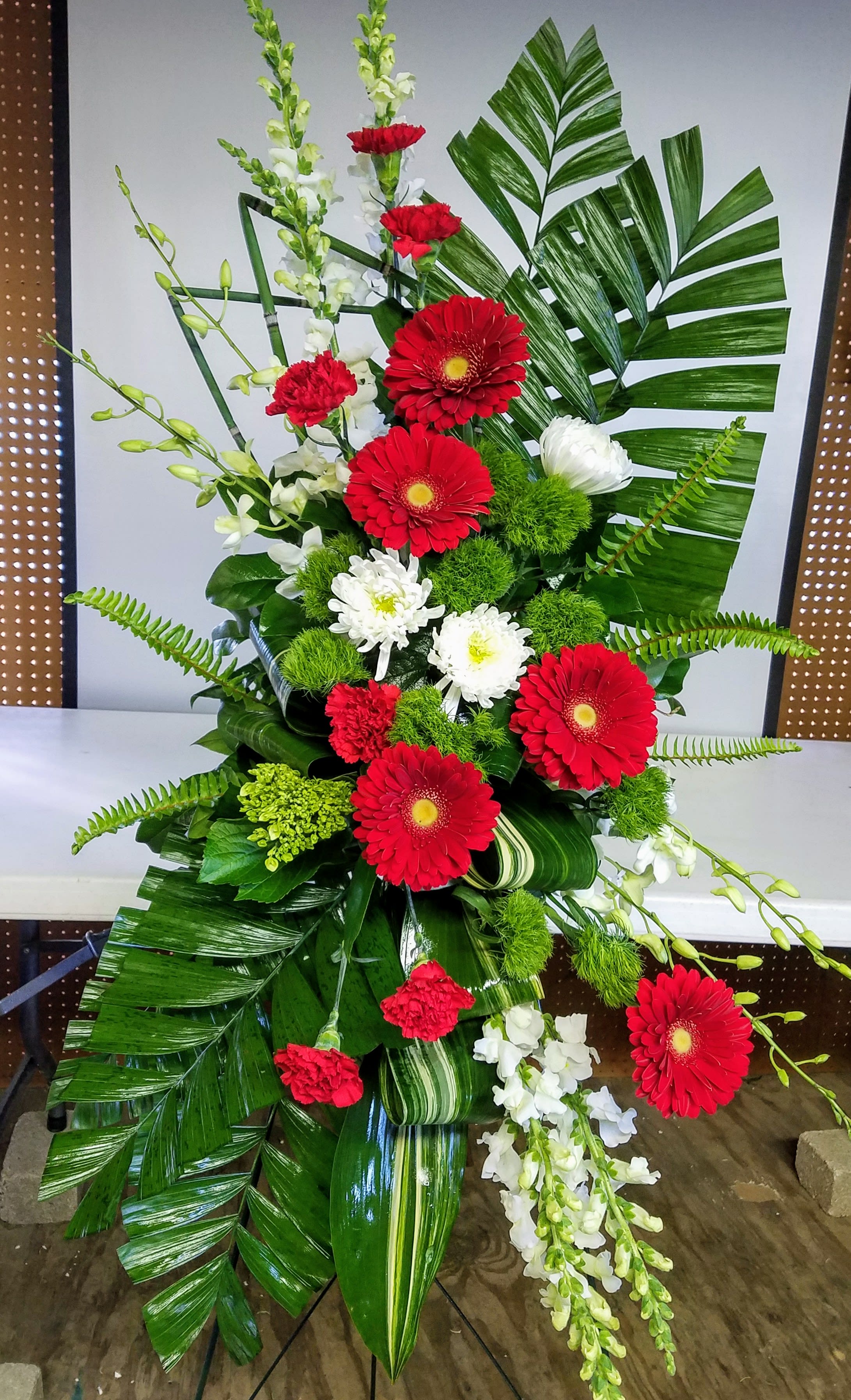 Tall floral spray with red and white flowers and large tropical leaves