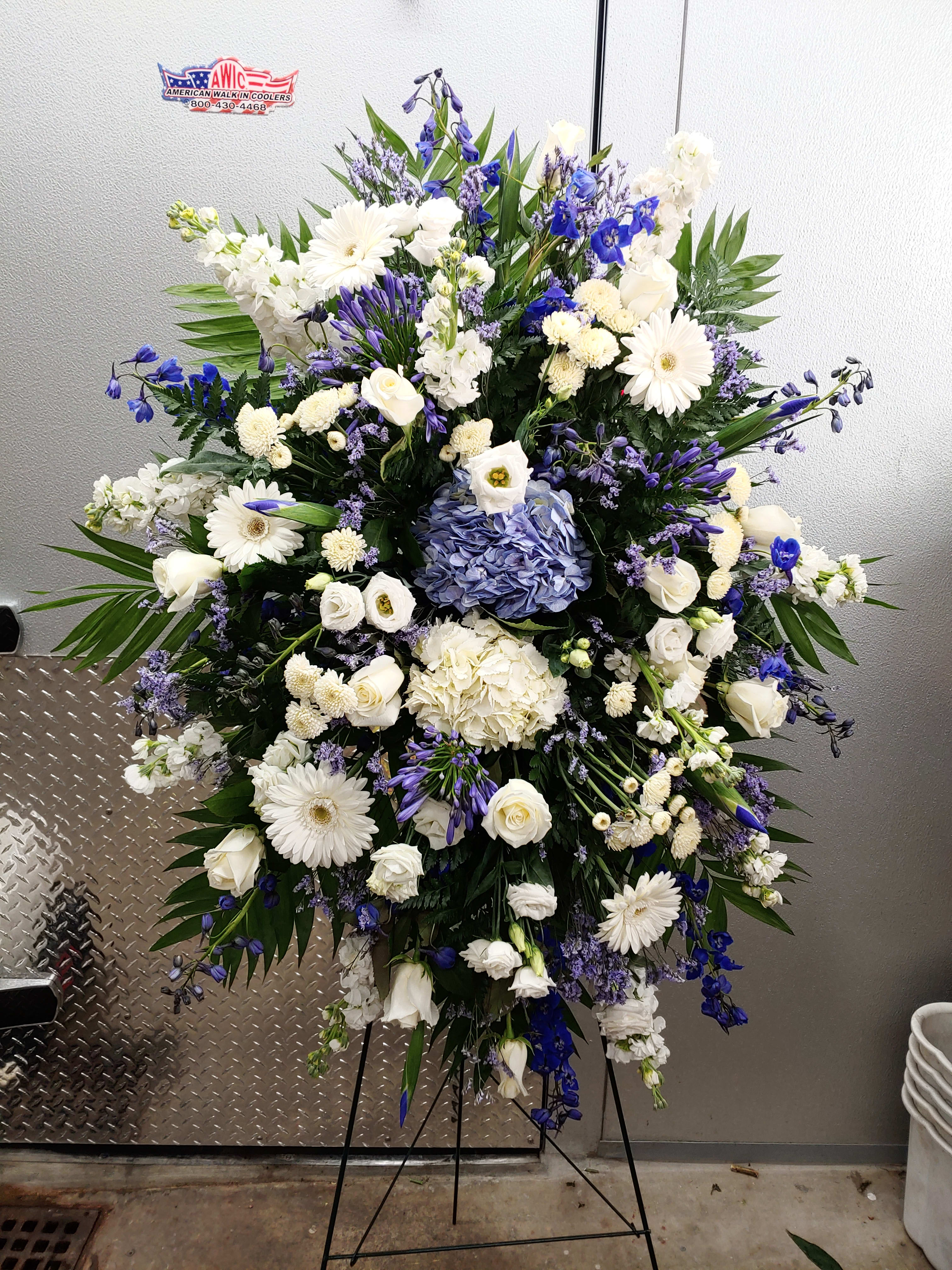 Large white and blue floral standing spray on an easel