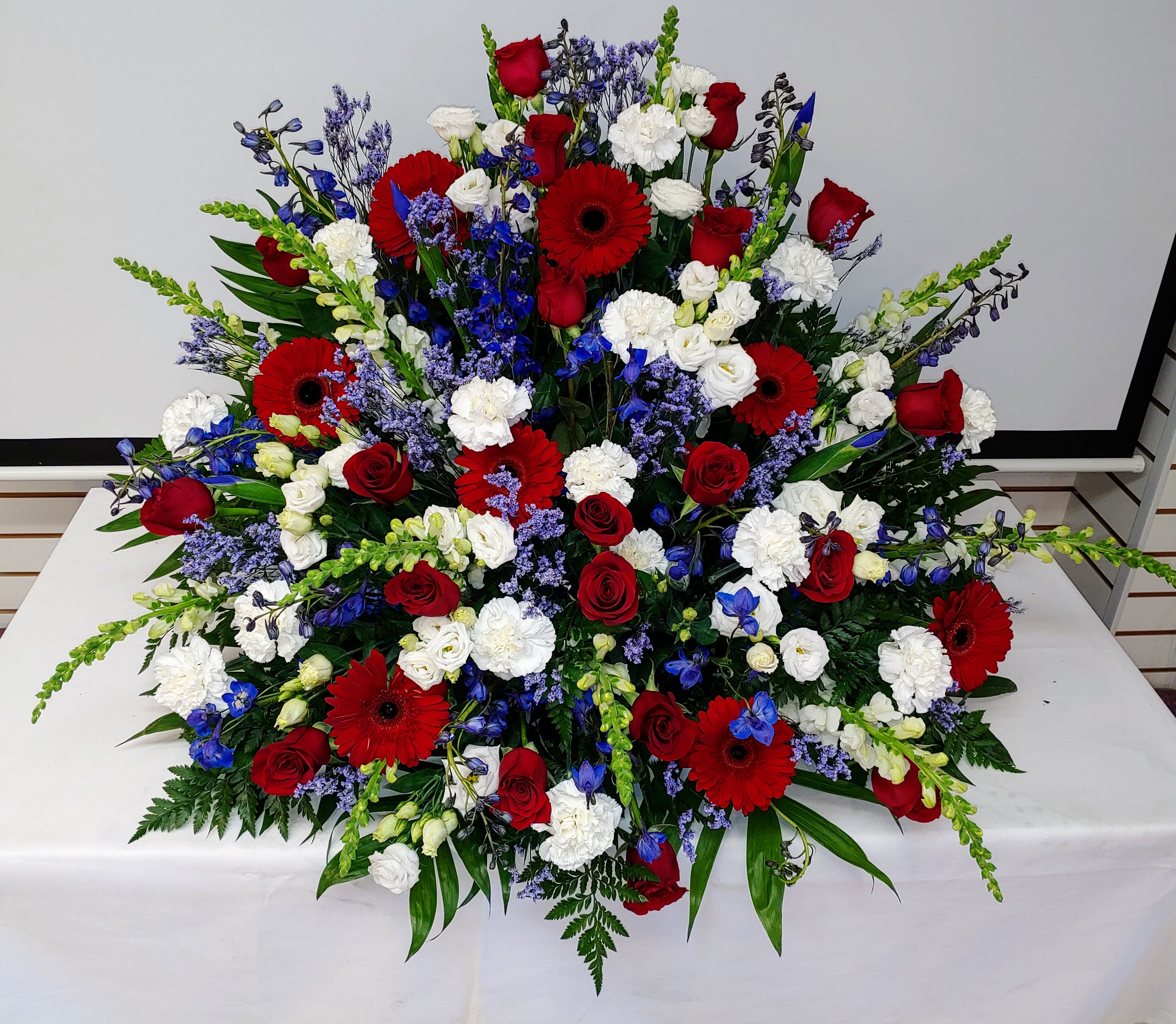 Large red, white, and blue floral spray with roses and gerbera daisies
