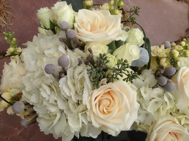 Cream roses and white hydrangeas in a bouquet with small lavender accents