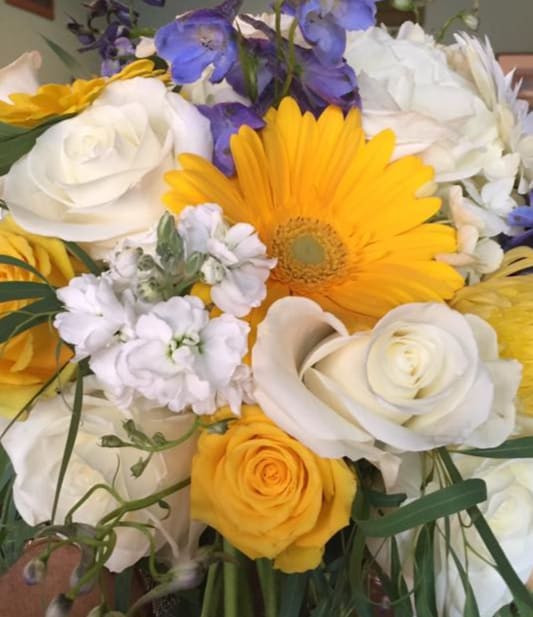 Bouquet of yellow, white, and purple flowers with a large yellow daisy