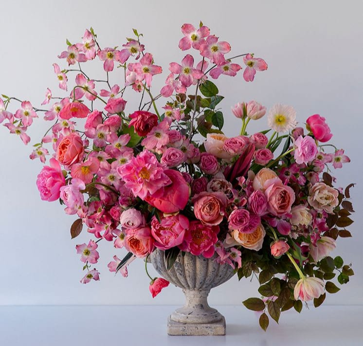 Pink floral arrangement in a stone urn vase
