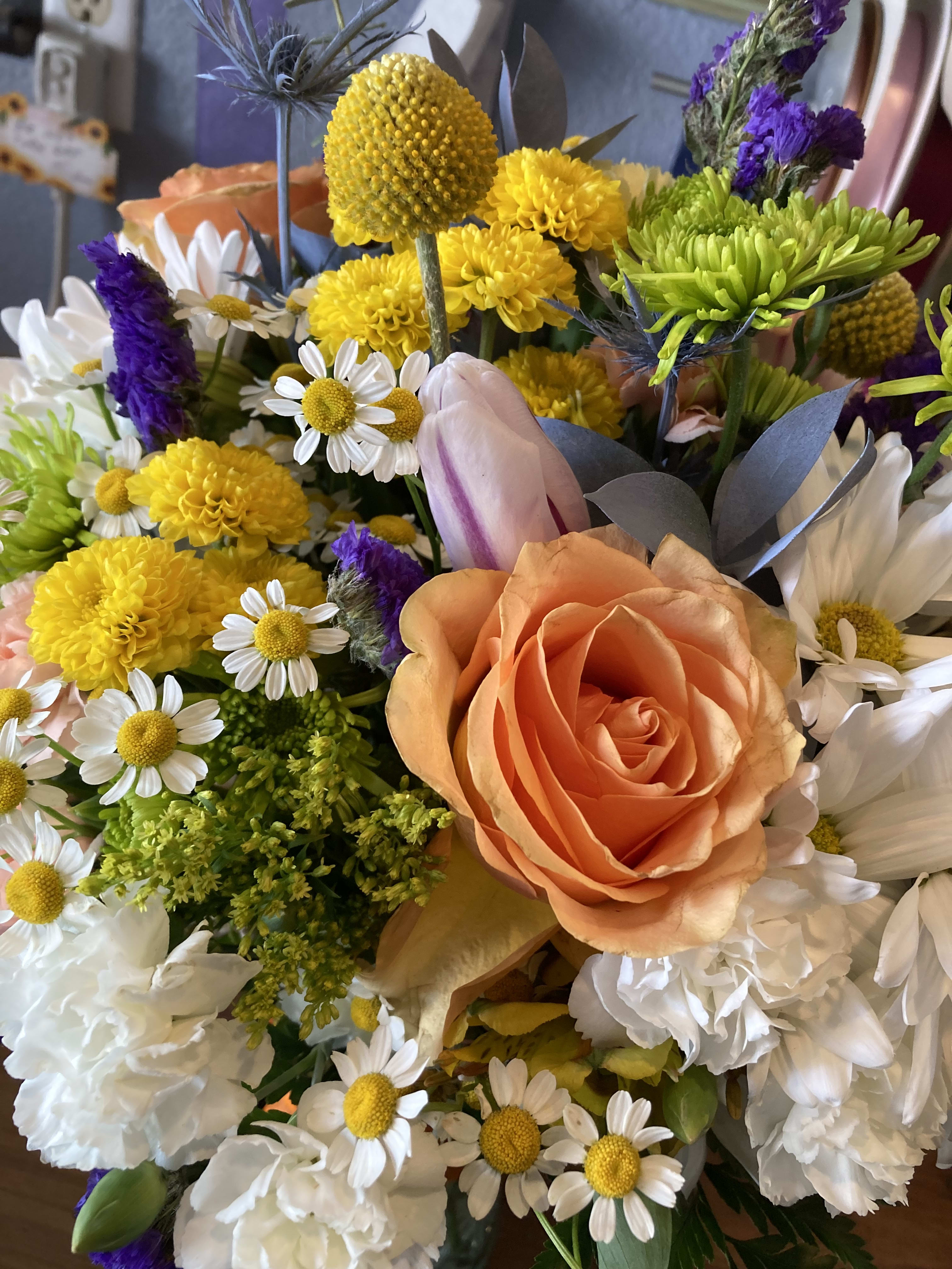 Mixed bouquet with peach roses, yellow blooms, and white daisies