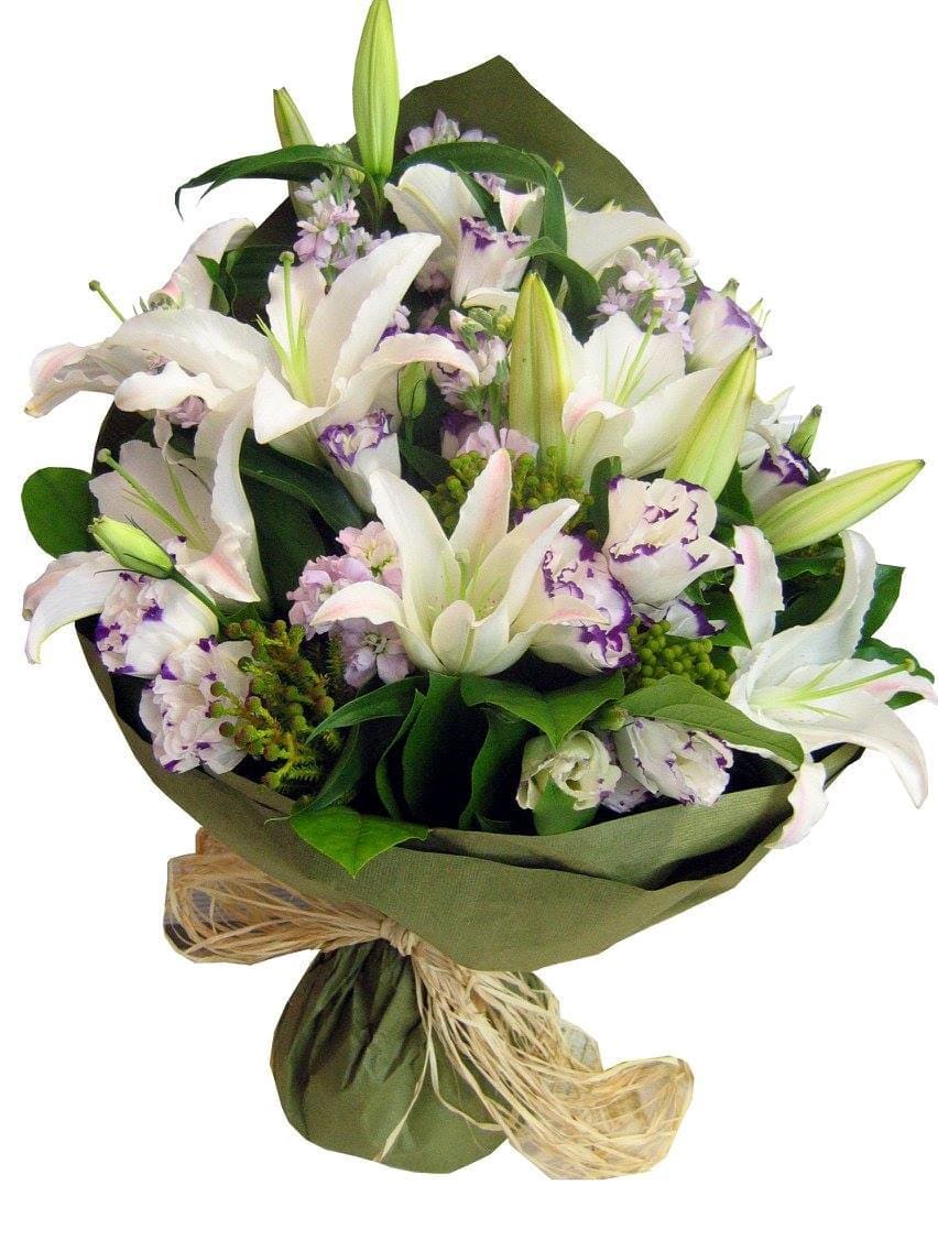Bouquet of white lilies and pale purple flowers wrapped in green paper