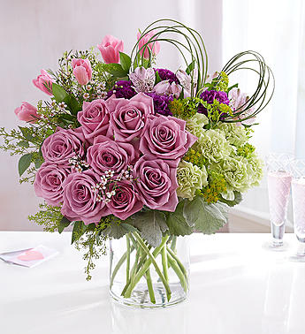 Pink roses and mixed flowers in a clear glass vase