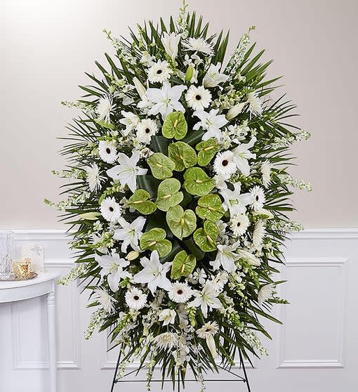White funeral spray with lilies, daisies, and green anthurium on a stand