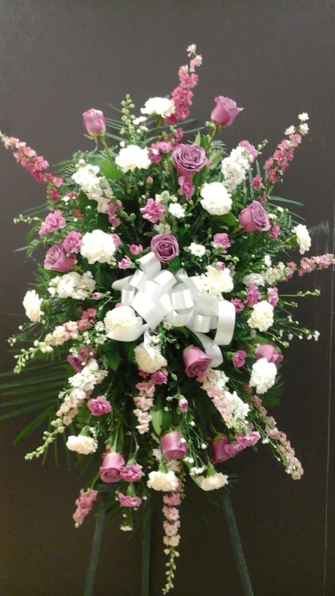 Large standing floral spray with pink and white flowers and a white ribbon bow