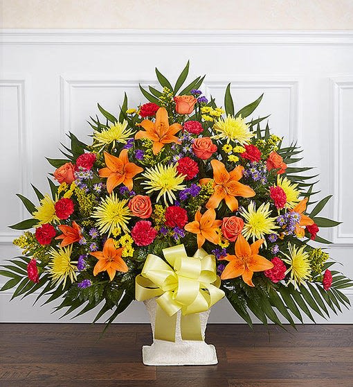 Large standing floral spray with orange lilies, yellow mums, and red roses