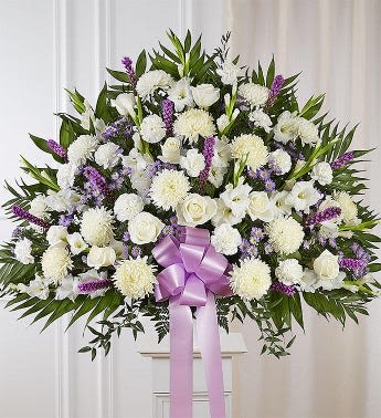 White floral standing spray with a purple ribbon bow