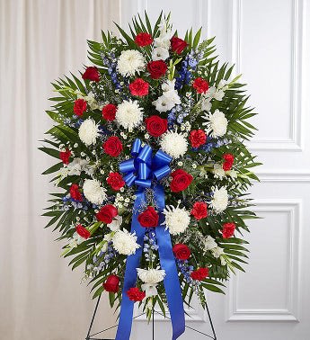 Standing funeral spray of red, white, and blue flowers on an easel