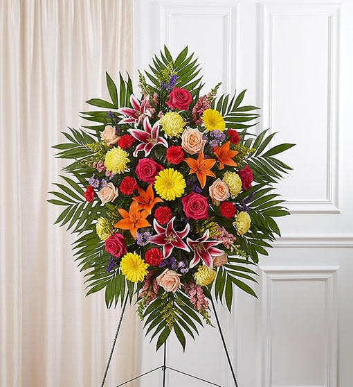 Standing floral spray with roses, lilies, and daisies on an easel