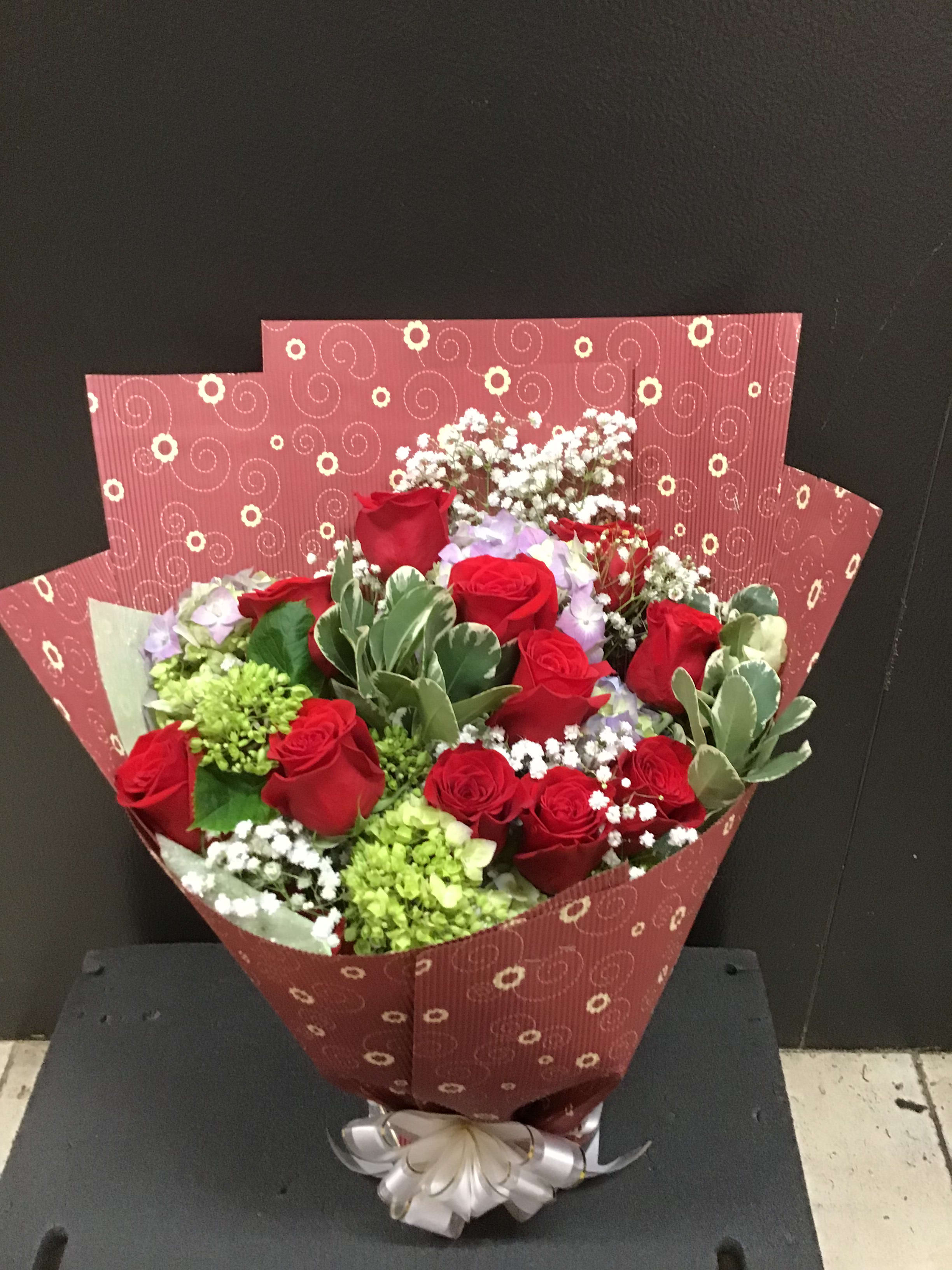 Bouquet of red roses with white filler flowers in patterned wrapping
