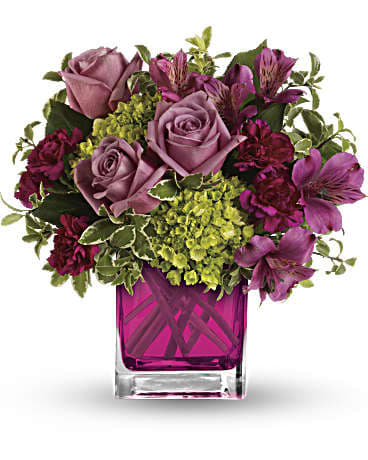 Pink roses and purple flowers in a square glass vase