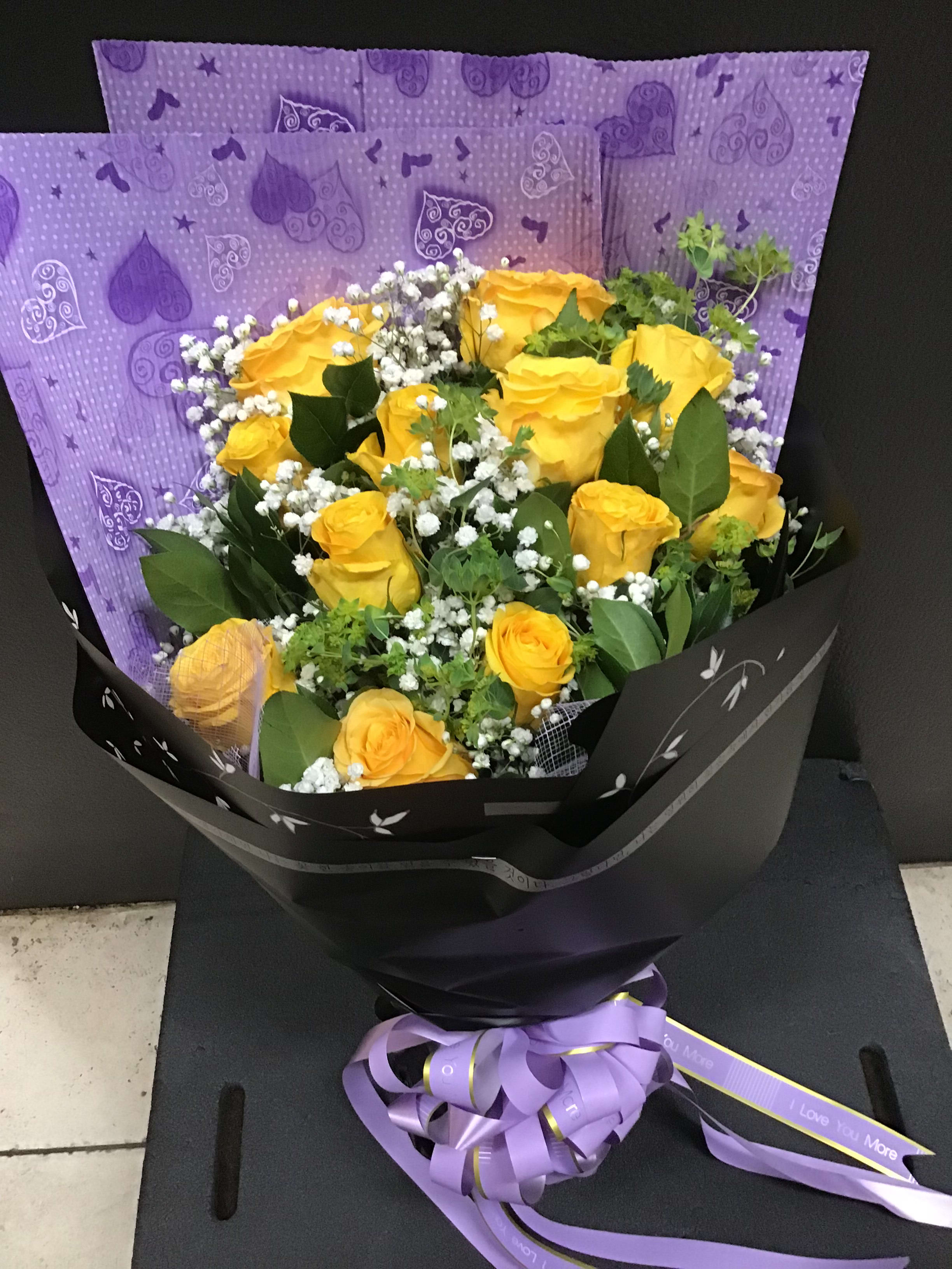 Bouquet of yellow roses with white baby's breath in black and purple wrapping
