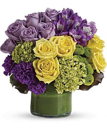 Purple and yellow roses in a green glass vase