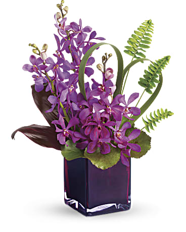 Purple orchid arrangement in a dark glass vase