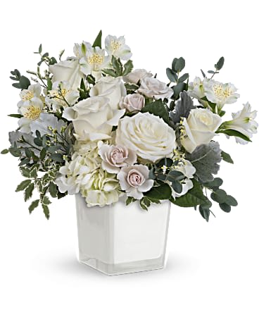 White roses and lilies in a clear square vase