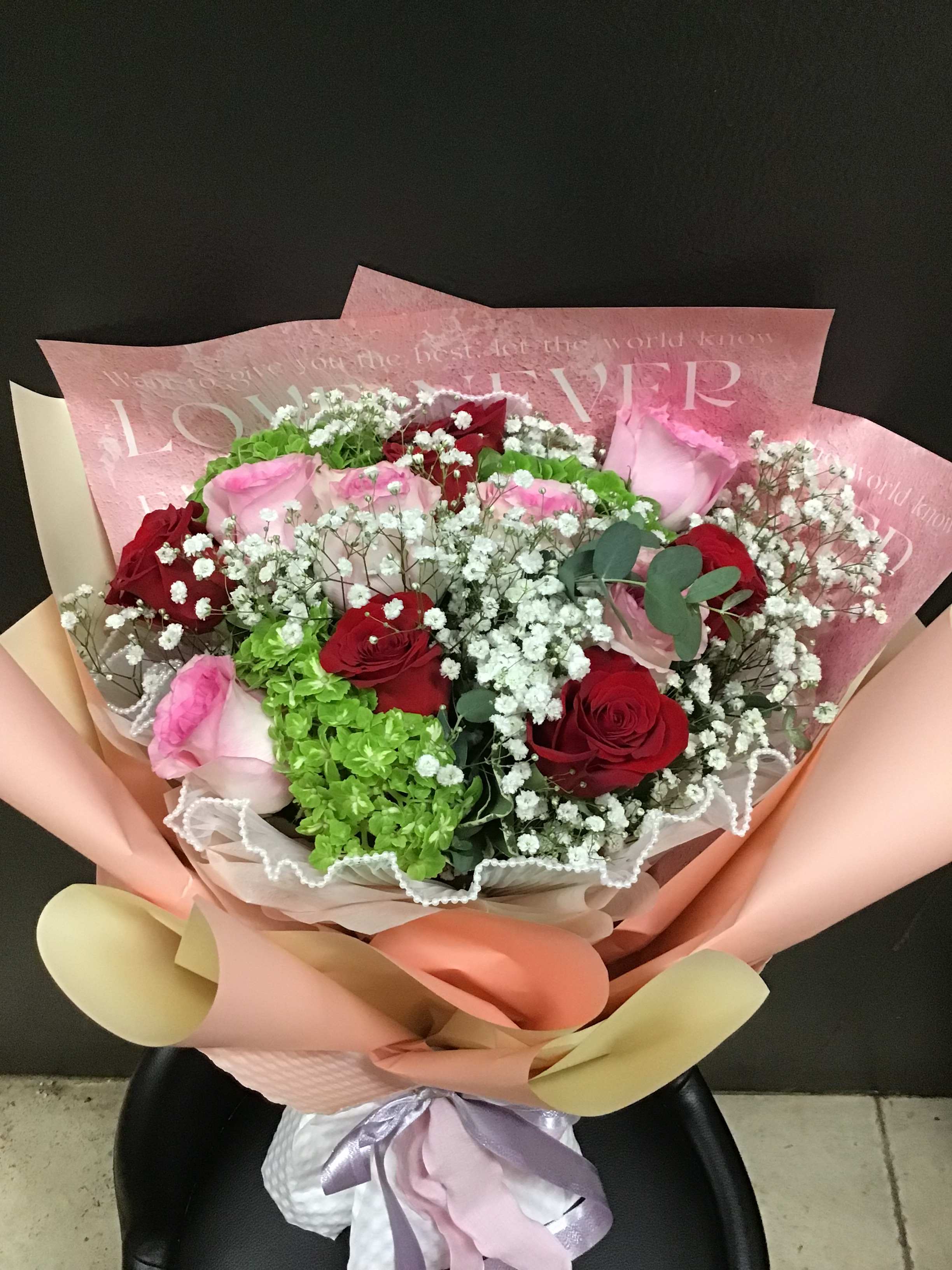 Bouquet of red and pink roses with white baby's breath in pastel wrapping