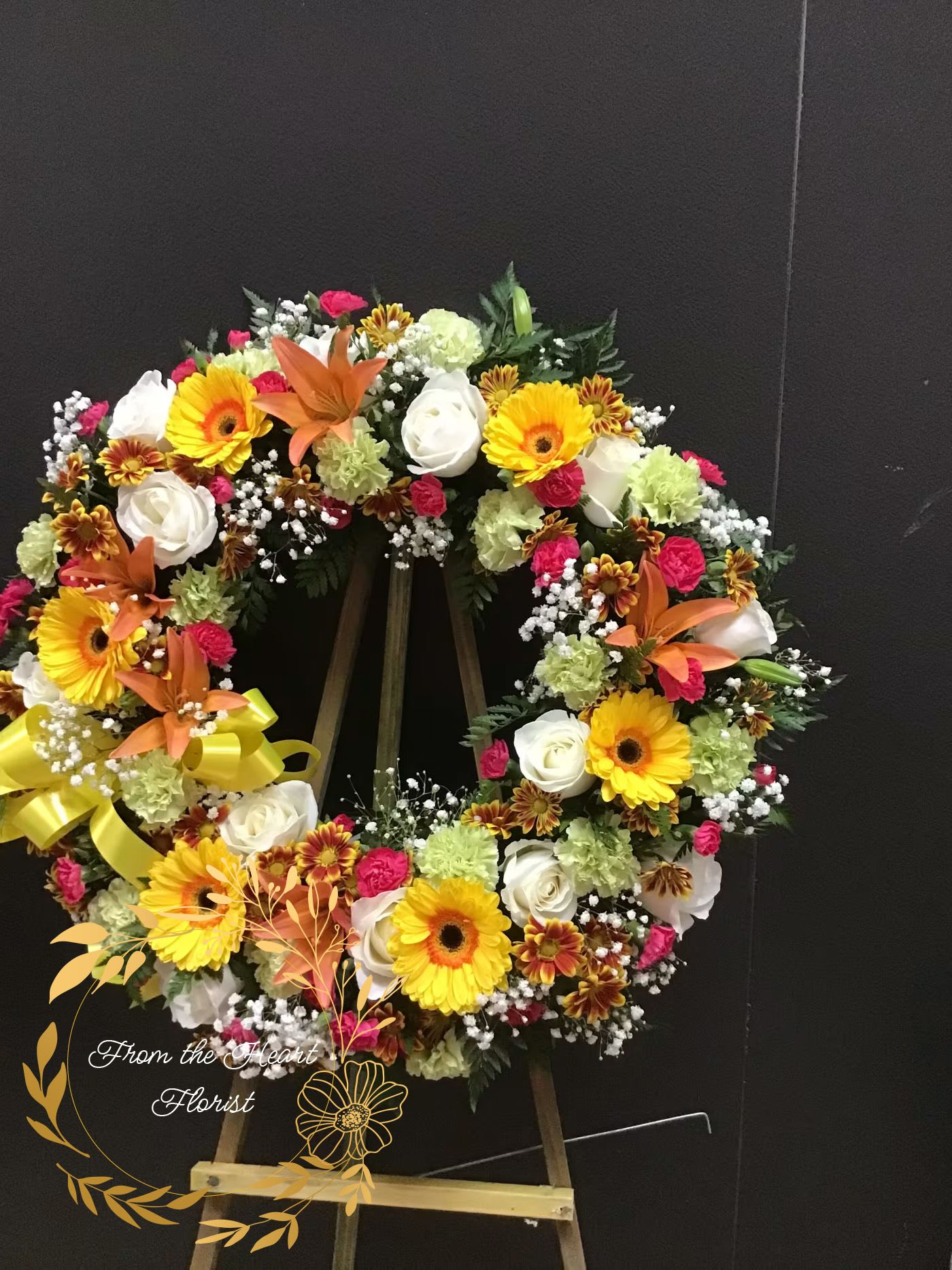 Heart-shaped floral wreath with yellow gerberas, white roses, and orange lilies