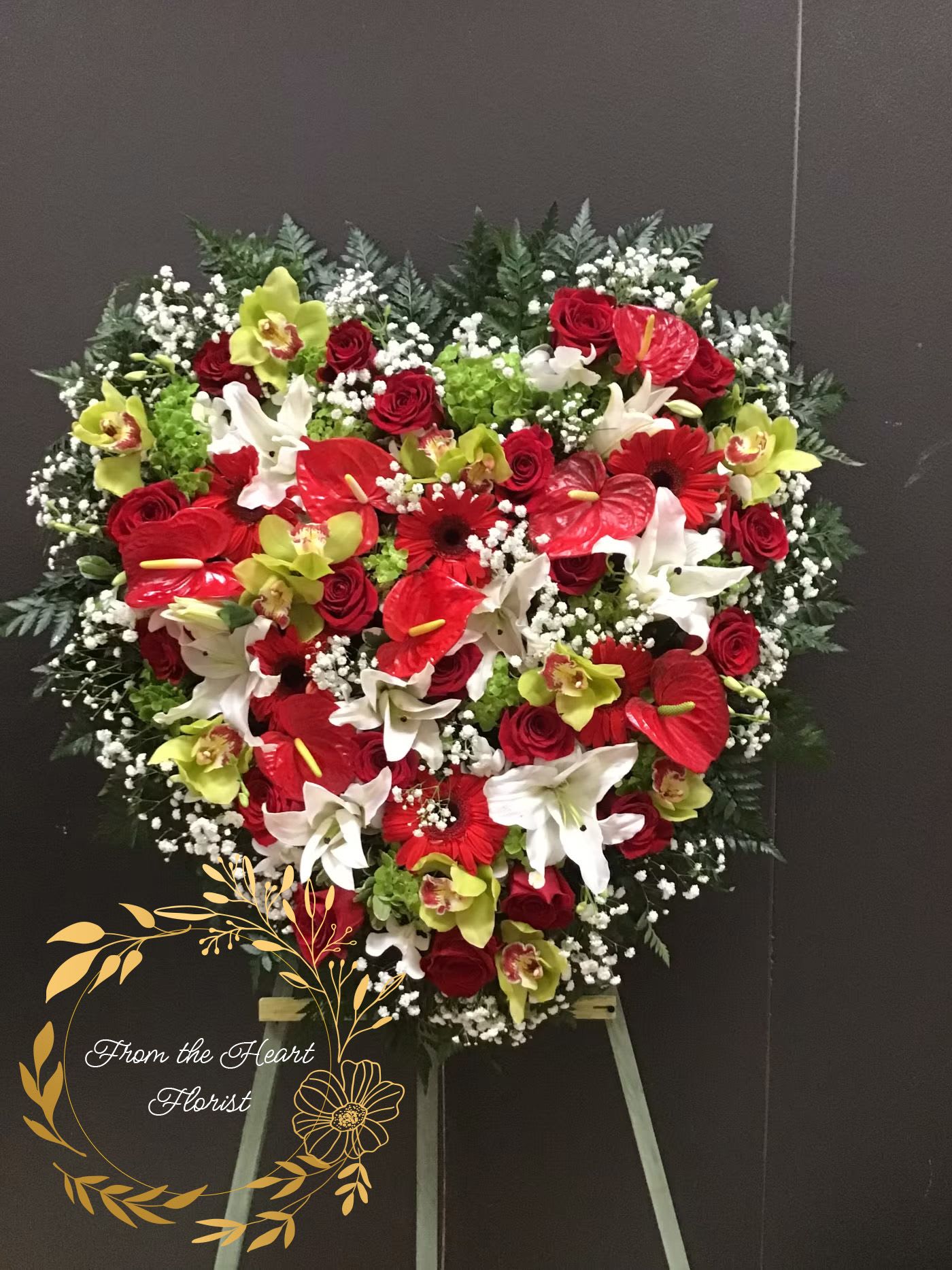 Heart-shaped floral spray with red, white, and green flowers on an easel